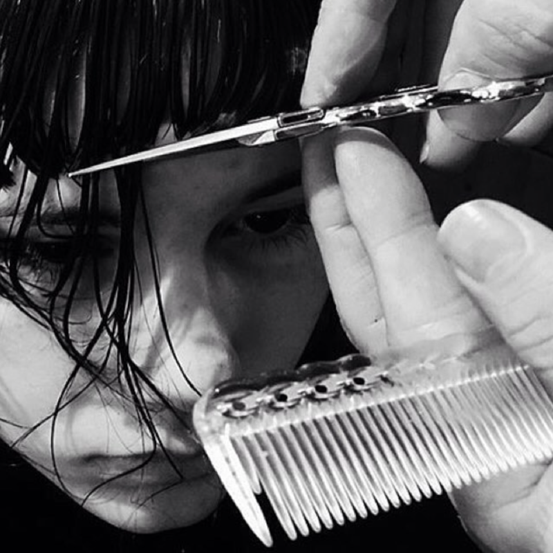 black and white up close photo of hair being cut with shears and comb in the frame 