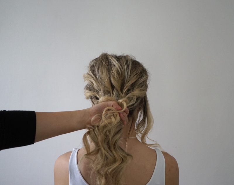 A person gathering hair into a ponytail for an updo